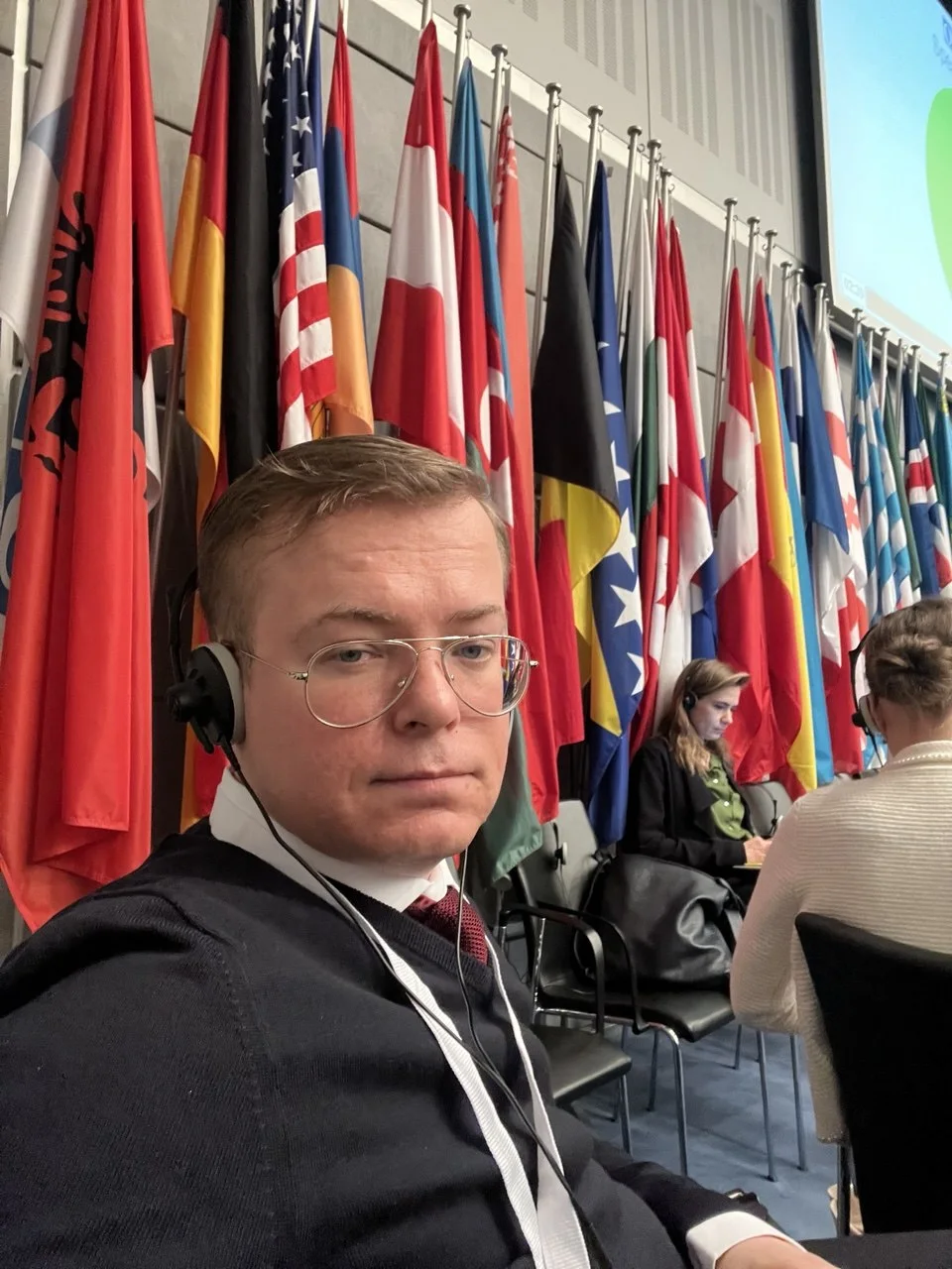 Aleksandr Shestakov in the OSCE meeting hall with participating States' flags